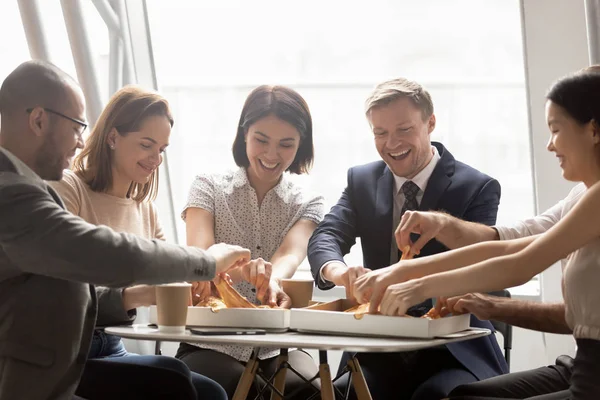 Felices trabajadores de la compañía mixta compartiendo almuerzo, comiendo pizza . — Foto de Stock