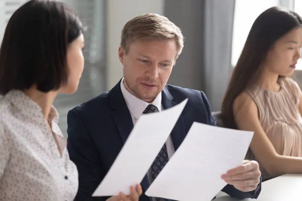Serious team leader reviewing financial report with asian female coworker. — Stock Photo, Image