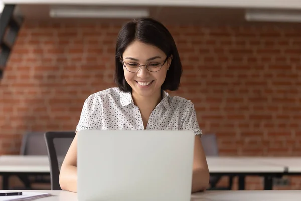 Happy asian business woman in glasses looking at computer screen. — Stock Photo, Image