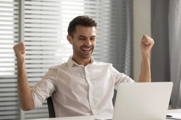 Jonge gelukkige mannelijke medewerker viert job promotie op kantoor. — Stockfoto