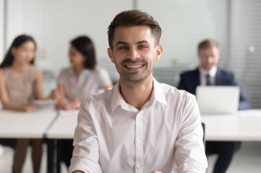 Ofiste oturan gülümseyen genç takım liderinin portresi.