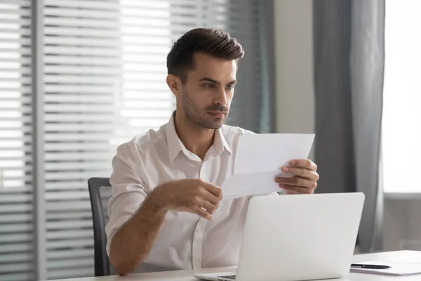 Concentrated young executive manager looking through financial documentation. — Stock Photo, Image