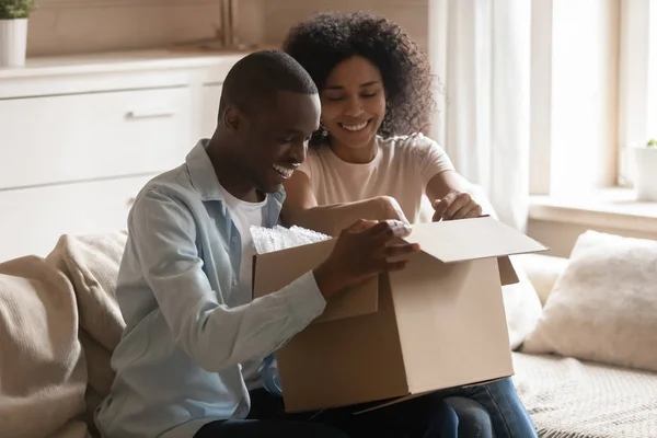 Emocionada pareja de clientes biraciales desempaquetar caja de entrega — Foto de Stock