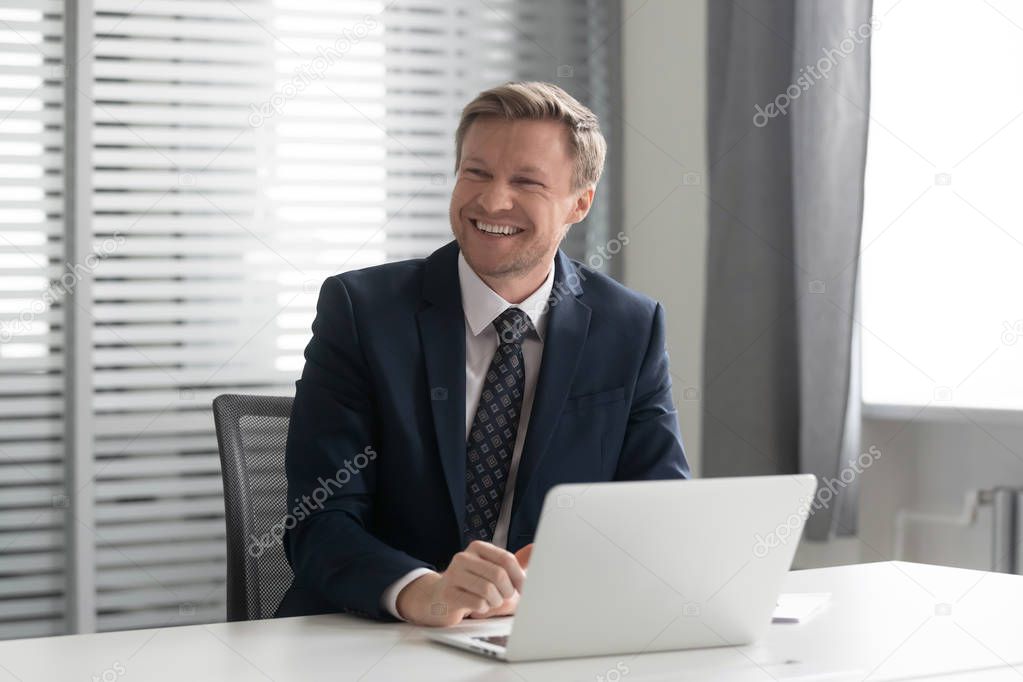 Happy businessman laughing, listening to joke, having fun at office.