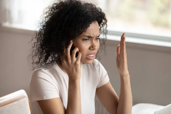 Unhappy biracial woman having unpleasant cellular call — Stock Photo, Image
