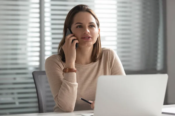 Serieuze jonge vrouwelijke leider die telefonisch praat met corporate client. — Stockfoto