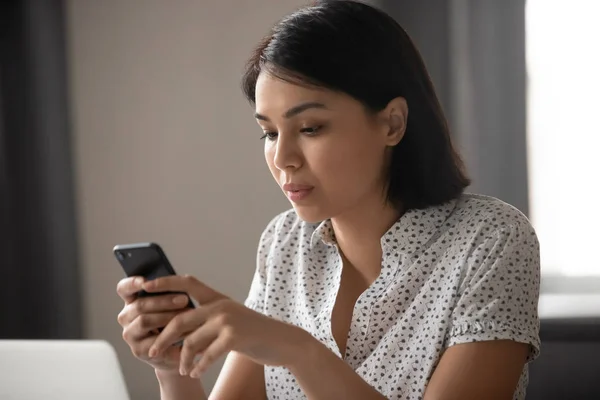 Geconcentreerde Aziatische Japanse zakenvrouw texting bericht in mobiele telefoon. — Stockfoto