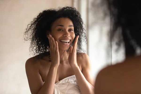 Senyum birasial wanita melihat di cermin melakukan prosedur wajah — Stok Foto