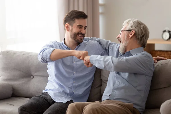 Happy senior father embracing young son giving fist bump