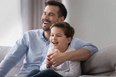 Mutlu baba ve çocuk oğlu kanepede tv izlerken gülüyor