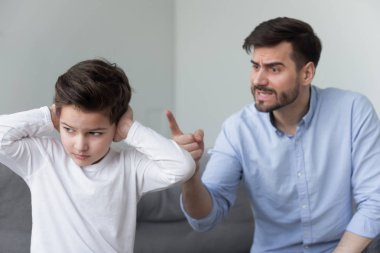 Kızgın baba inatçı telaşlı küçük oğlu kulakları kapatarak bağırıyor