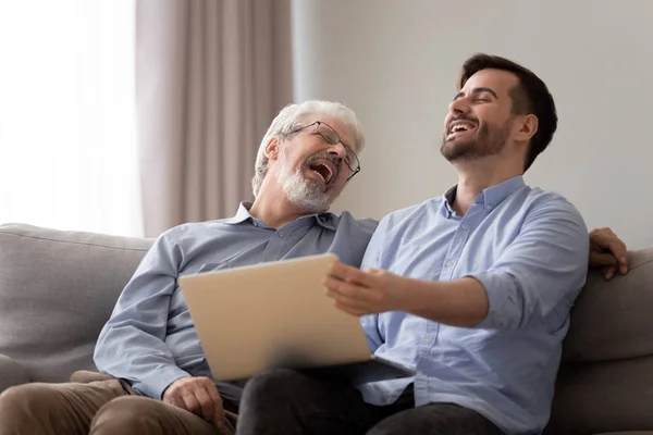 快乐的老父亲和年幼的儿子笑用笔记本电脑在一起 — 图库照片