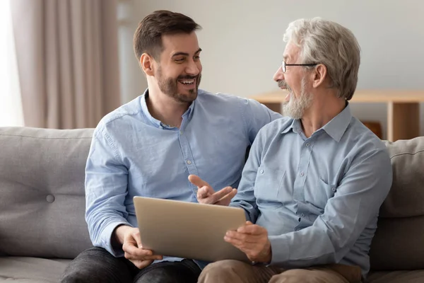 Feliz padre viejo emocionado y joven hijo hablando con el ordenador portátil — Foto de Stock