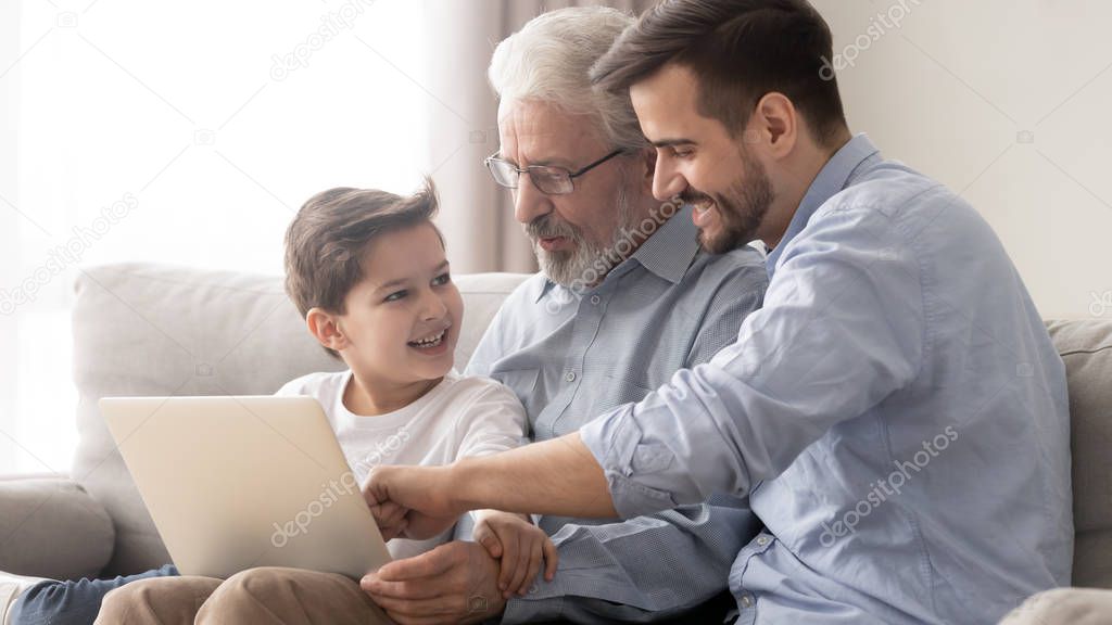 Happy three generation family grandfather father and grandson using laptop
