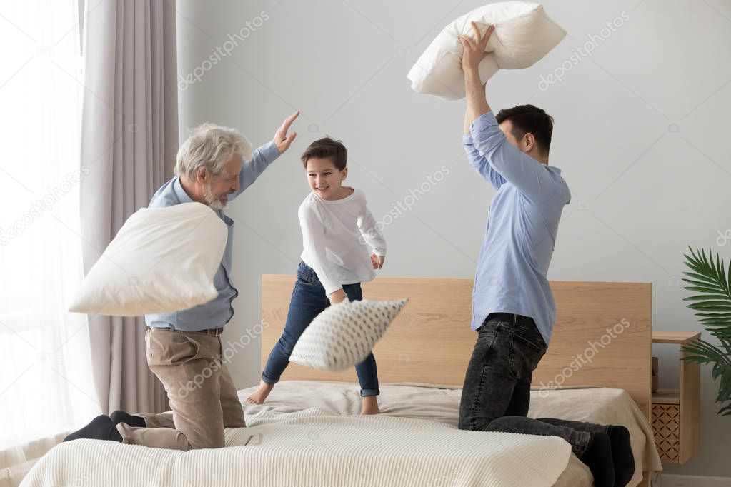 Happy three generations men family having pillow fight on bed