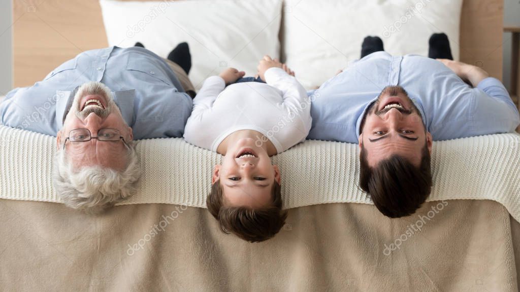 Happy three generation family lying upside down on bed, portrait