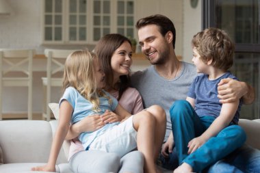 Mutlu genç aile çift kucağında küçük sevimli çocuklar tutmak.