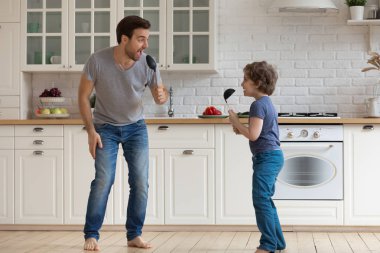 Mutlu oğlu çorba kepçe tutan tam uzunlukta genç baba.