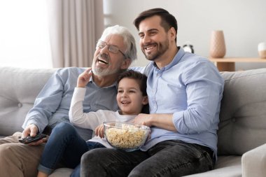 Mutlu üç nesil erkek aile uzaktan kumanda tutun tv izle