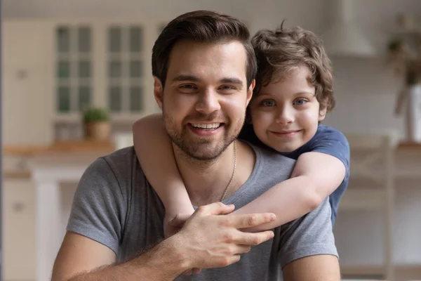 Glücklicher kleiner süßer Junge umarmt lächelnden jungen Vater. — Stockfoto