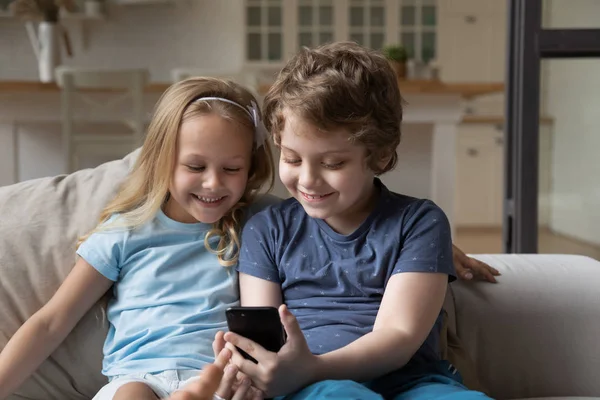 Smiling joyful little kids sibling using smartphone apps . — стоковое фото