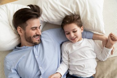 Genç baba yatakta yatan çocuk oğlu kucaklayan, üst görünümü