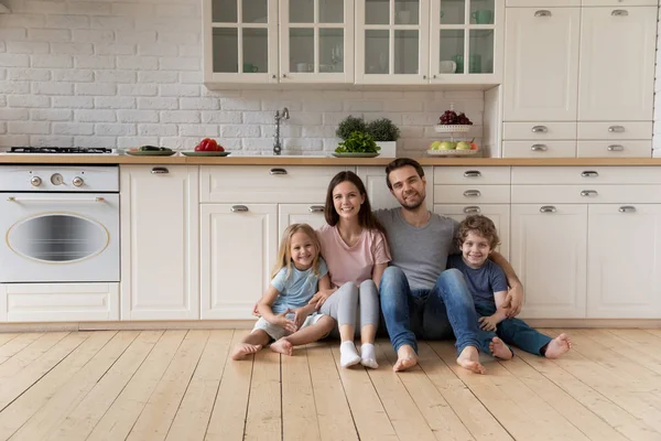 Porträt einer glücklichen Familie, die in der Küche auf dem Boden sitzt. — Stockfoto