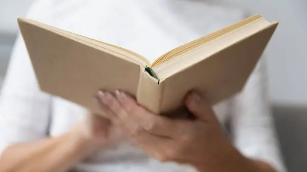 De cerca mujer madura sosteniendo libro de papel abierto en las manos —  Fotos de Stock