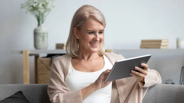 Wanita dewasa tersenyum menggunakan aplikasi tablet komputer, bersenang-senang — Stok Foto