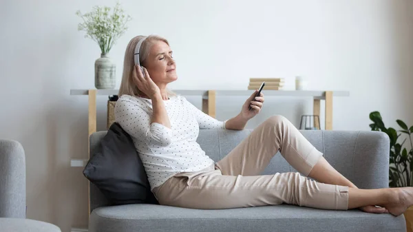 Reife Frau mit Kopfhörer genießt Lieblingsmusik, mit dem Handy — Stockfoto