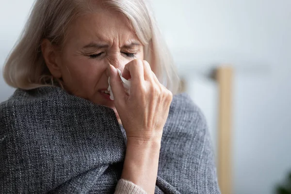 Unhappy mature woman covered blanket feeling bad, sneezing — Stock fotografie