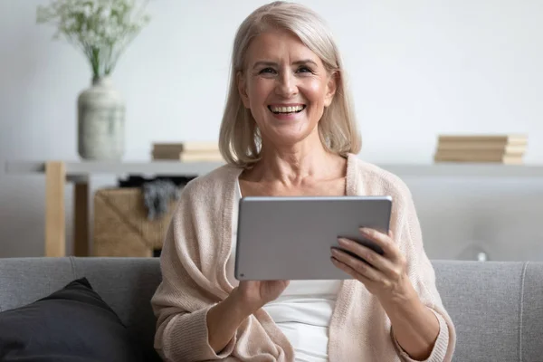 Wanita dewasa yang bahagia menggunakan tablet komputer, menertawakan lelucon lucu — Stok Foto