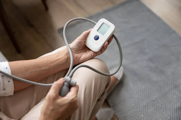 Close up mature woman measuring blood pressure with digital tonometer — Stock Photo, Image