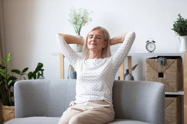 Glücklich entspannte ältere Frau sitzt zurückgelehnt auf der Couch — Stockfoto