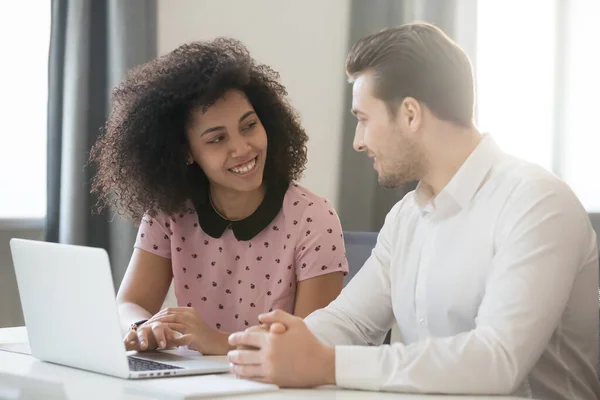 Multiracial company members sitting at desk talking and smiling — Stock Photo, Image