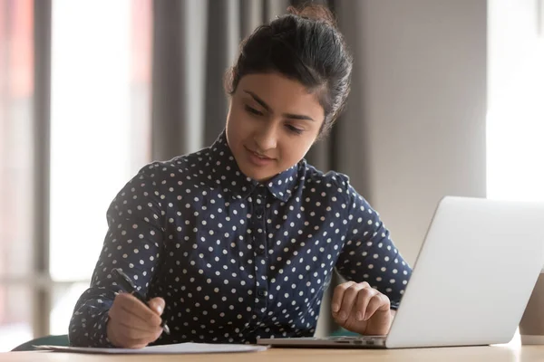 Young indian businesswoman student working studying with laptop making notes