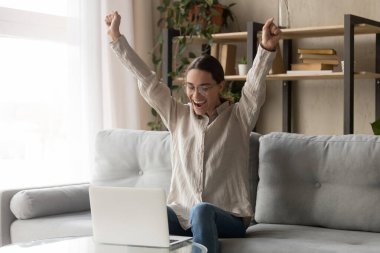 Kazananı kutlayan heyecanlı kız öğrenci laptopa bakıyor.