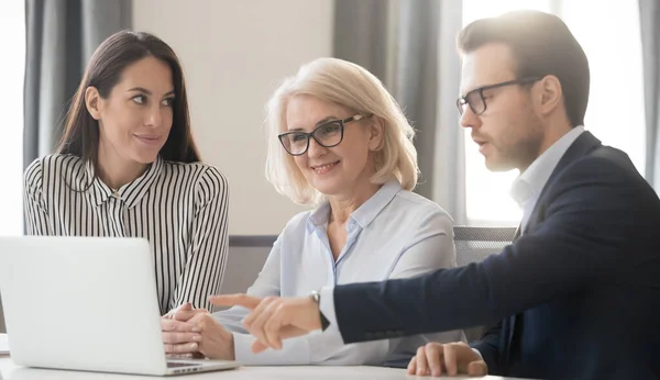 Businesspeople gather together in office sitting at desk using laptop — Stock fotografie