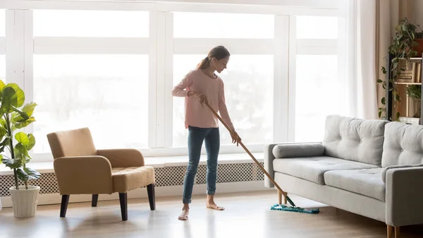 Молодая женщина домохозяйка чистый пол в современной гостиной — стоковое фото