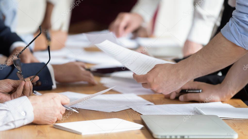 Close up of employees discuss financial paperwork at meeting