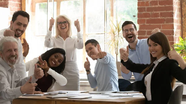 Excited diverse colleagues show thumbs up gathering at meeting