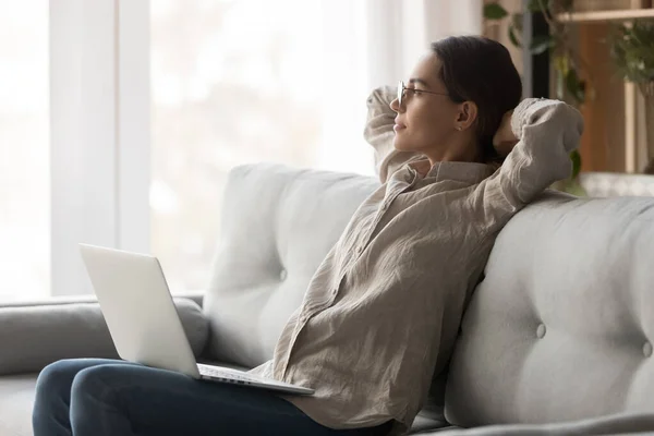 Happy dreamy woman relaxing stretching sit on couch with laptop — Stock Photo, Image