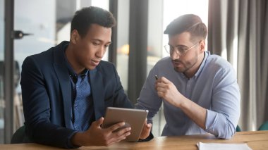 Dijital tablet kullanarak projeyi tartışan siyah ve beyaz ortaklar
