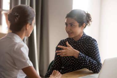 Serious indian mentor worker talk to female colleague teach intern clipart