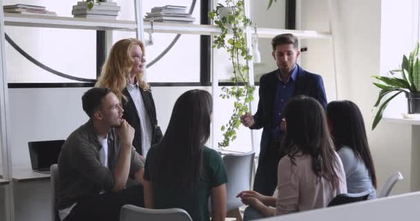 Счастливая мультирасовая бизнес-команда и наставник разговаривают смеясь на рабочем месте — стоковое видео