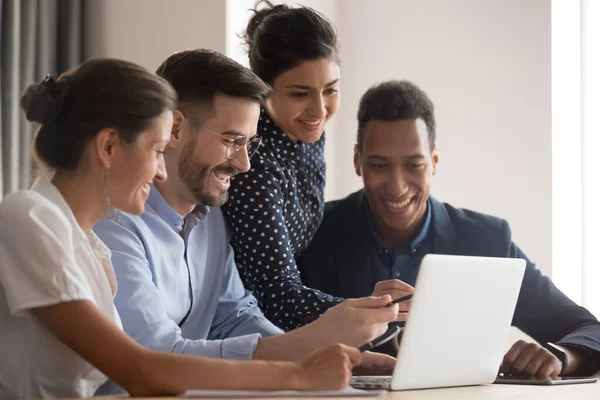 Glimlachende diverse etniciteit medewerkers groep verzamelen op zoek te wijzen naar laptop — Stockfoto