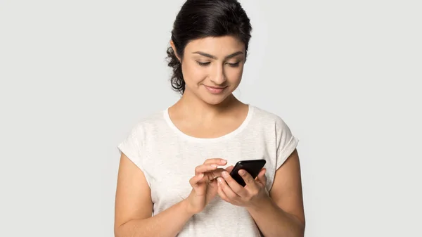 Ethnic girl isolated on grey background using cellphone — Stock Photo, Image