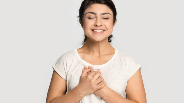 Sonriente chica india cogida de la mano en el pecho se siente agradecida —  Fotos de Stock