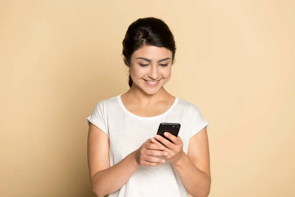 Щаслива етнічна дівчина посміхається, використовуючи сучасний текст смартфона — стокове фото