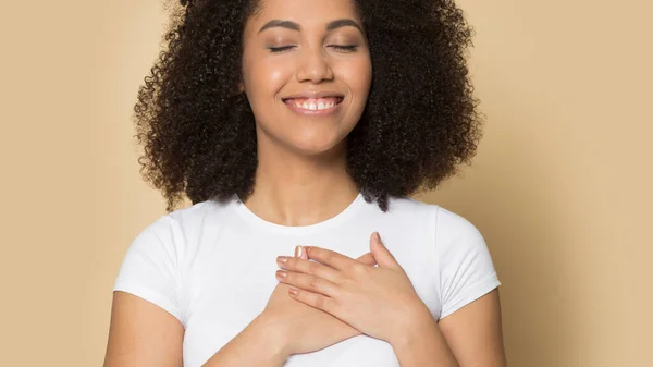 Благодарная расовая девушка с руками на груди чувствует благодарность — стоковое фото